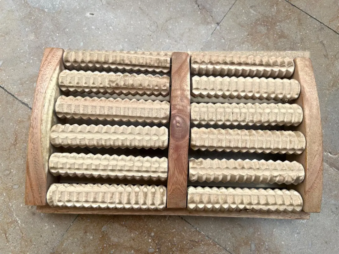 Wooden foot massager seen from above: a wooden frame with two sections of carved wooden rollers