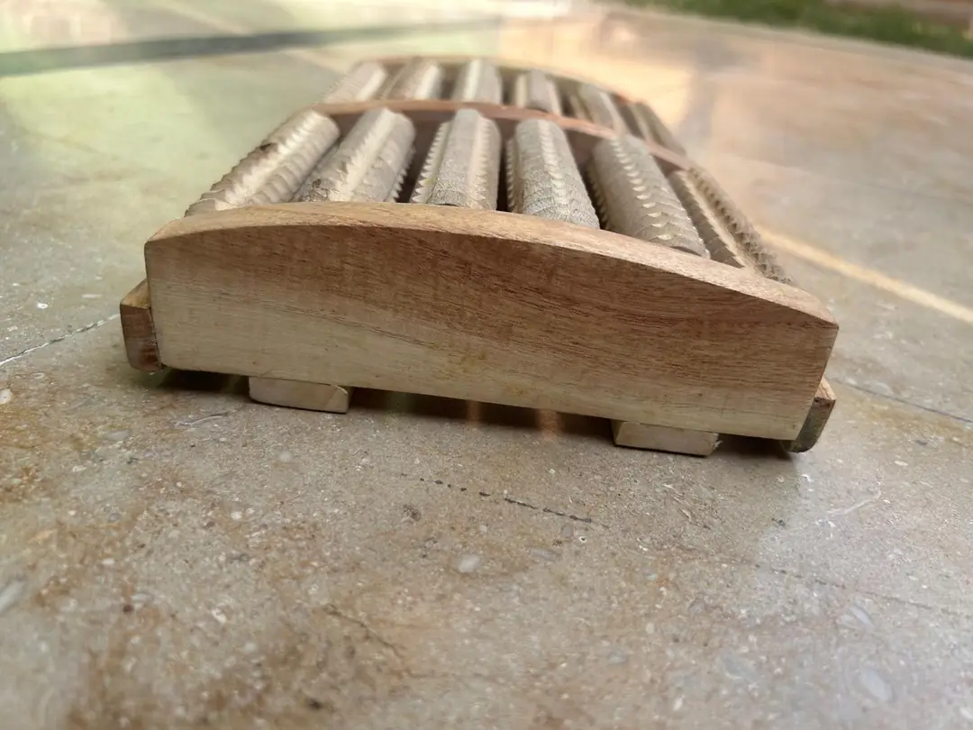 Side view of the dual wooden foot massager showing its ridged rollers