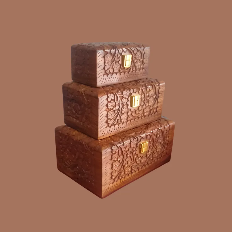 Three hand-carved sheesham jewellery boxes stacked largest to smallest, each carved with a floral vine and closed with a brass clasp
