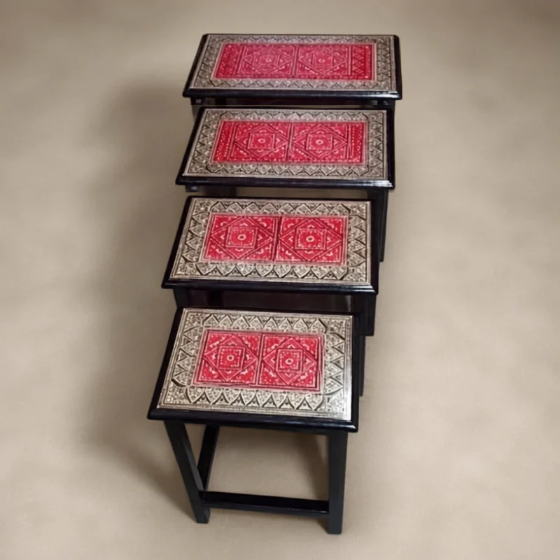 Four nesting tables with red lacquer tops and silver patterned borders