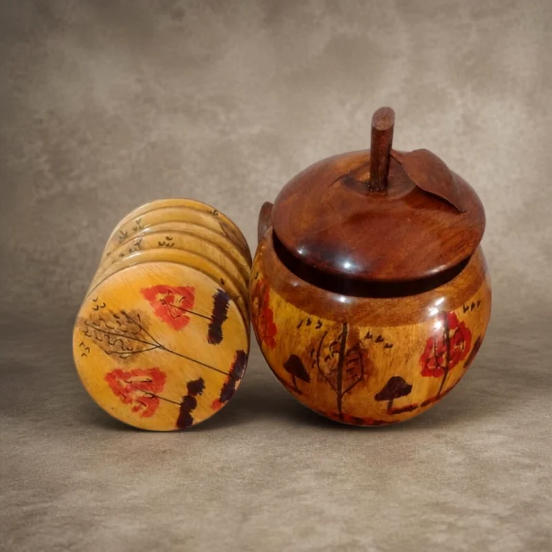 Apple-shaped hand-painted wooden holder beside a stack of six matching painted tea coasters