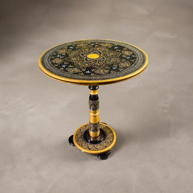 Round pedestal table with a black and gold naqshi top and a banded turned stem