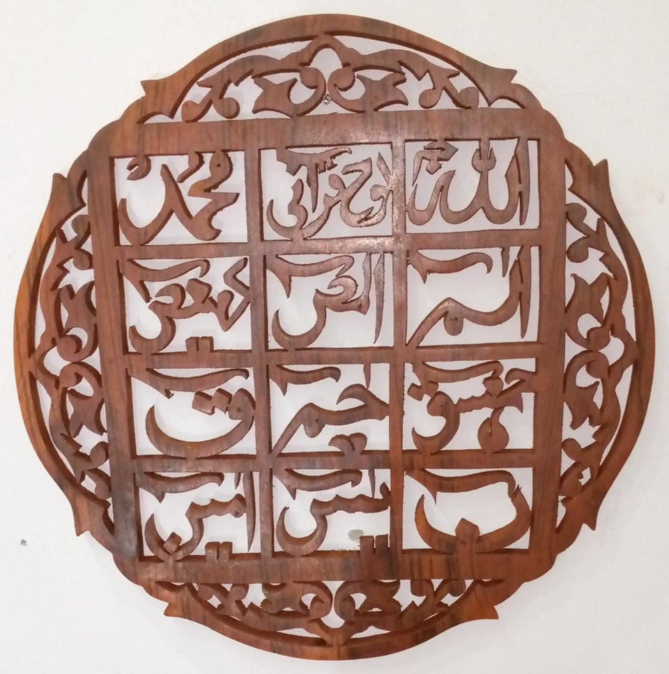 Round carved wooden wall panel with Quranic verses in a grid