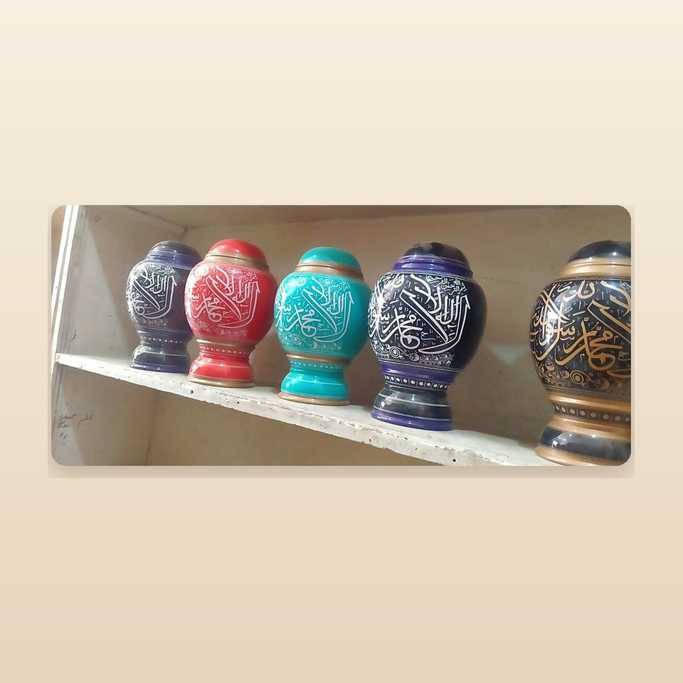 Row of coloured lacquer jars with the Kalima written around each in white