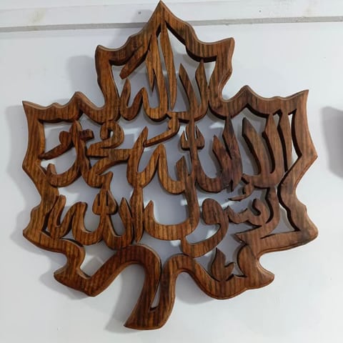 Kalima carved into a leaf-shaped wooden wall panel