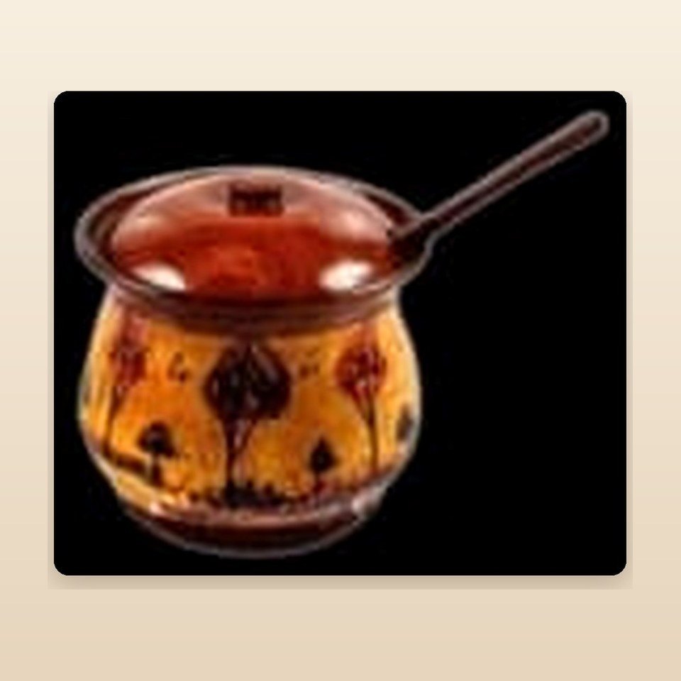 Small orange naqshi lidded pot with a long wooden spoon resting through the lid