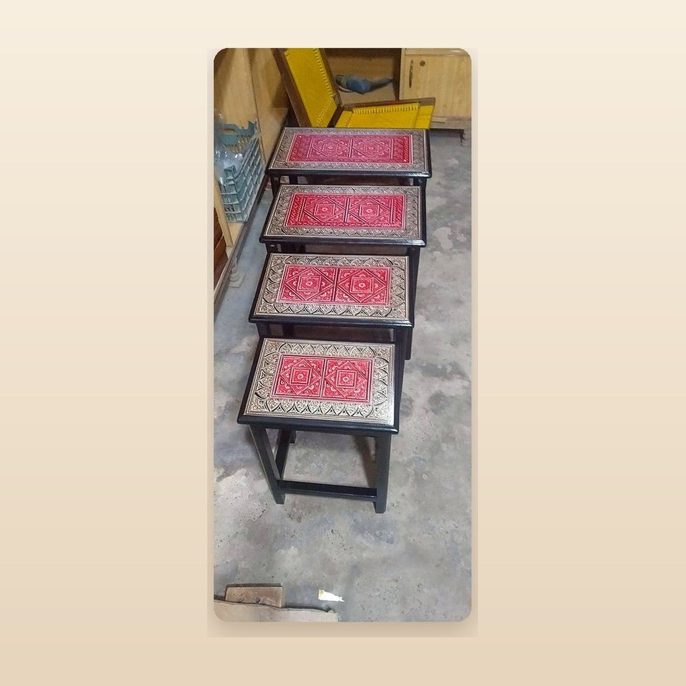 Four nesting tables with red lacquer tops and silver patterned borders