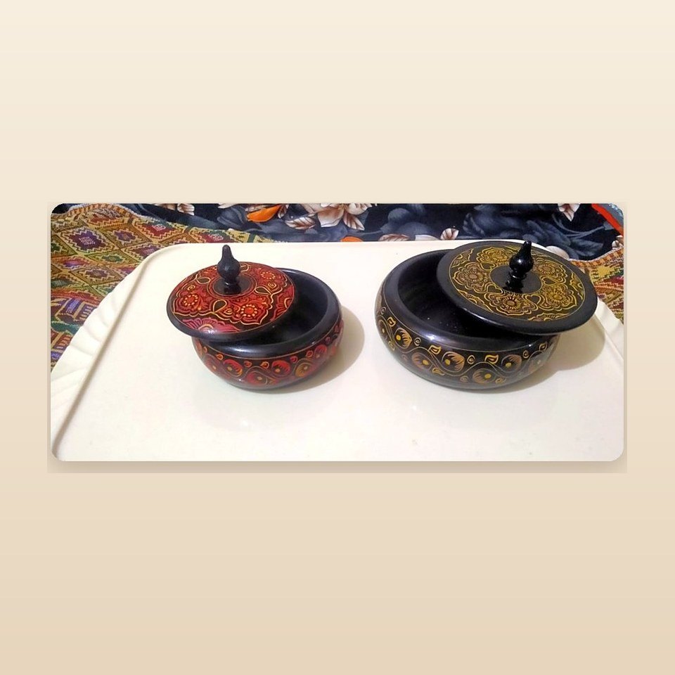 Two round painted boxes with pointed finials, one red and one black with gold