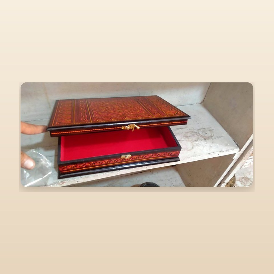 Red and gold lacquered Quran box open to show the red cloth lining